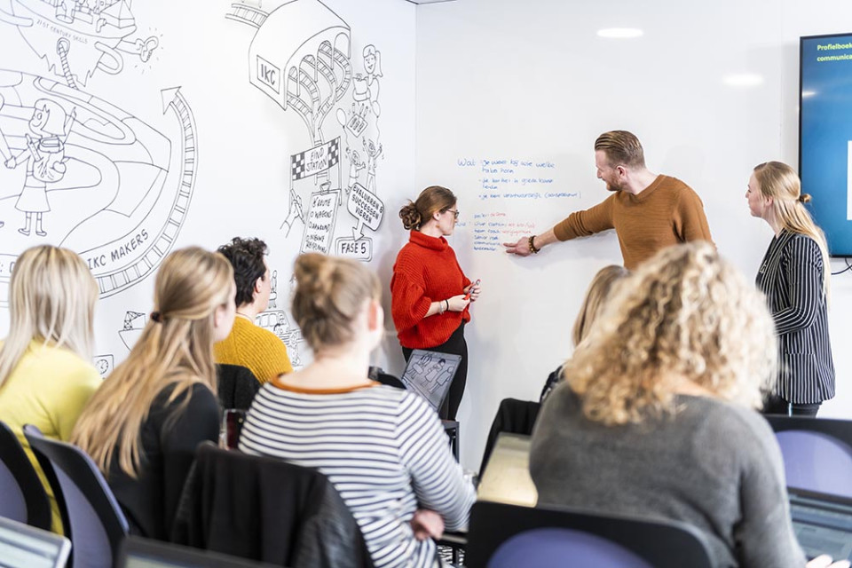 Docent met studenten in een klaslokaal.