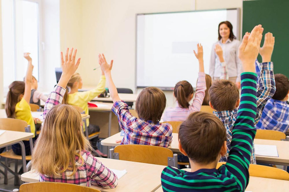 Een juf geeft les aan leerlingen in een klas.