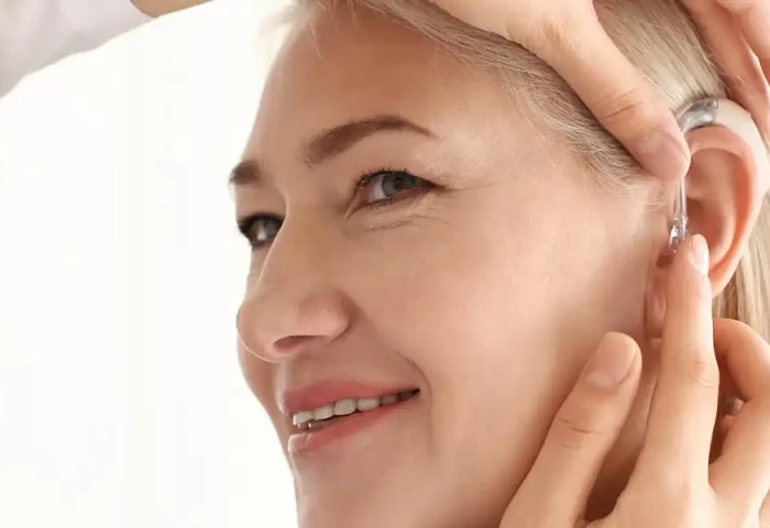 Audicien plaatst een hoorapparaat bij een klant